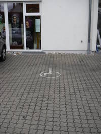 Behindertenparkplatz senkrecht zur Straße, links neben dem Gebäude / Apothekeneingang 